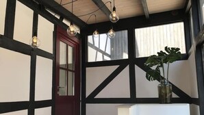 A room with exposed wooden beams, a white bench, a potted plant, and hanging light fixtures. - Eichhaus Eifel (Rheinbach)