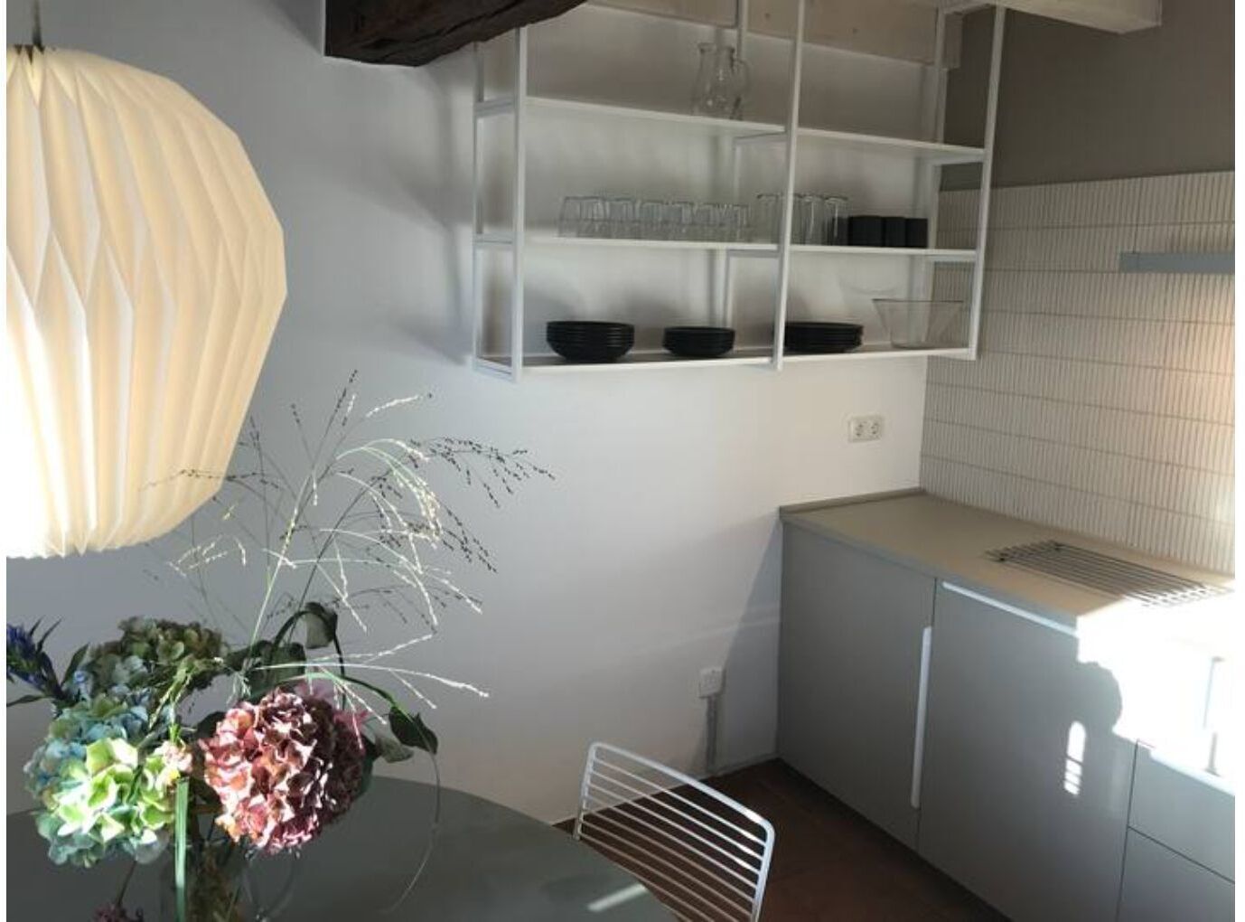 A kitchen with white cabinets, a white countertop, and a hanging light fixture.