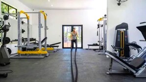 A gym with exercise equipment, a treadmill, and a large window. - Private Studio with Kitchenette including Breakfast (Cape Town)