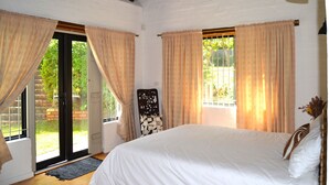 A bedroom with a large bed, a chair, and a window with curtains. - Private Studio with Kitchenette including Breakfast (Cape Town)