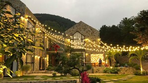 A stone building with a stone facade and a large glass window. There are string lights hanging above the entrance. - TICO VILLA TAM DAO (Tam Dao)