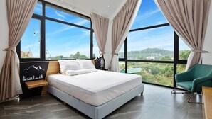 A modern bedroom with a large bed, a nightstand, a green chair, and a view of a green landscape through large windows. - TICO VILLA TAM DAO (Tam Dao)