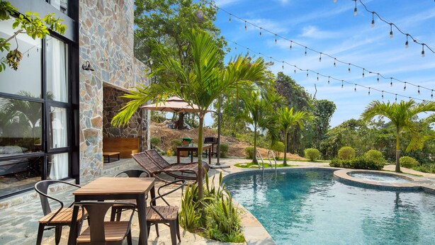 A poolside area with a stone wall, outdoor seating, and string lights. - TICO VILLA TAM DAO (Tam Dao)