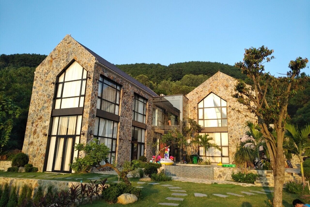 A stone building with large windows and a well-maintained garden.