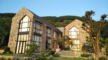 A stone building with large windows and a well-maintained garden.