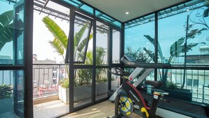 A modern room with large windows, a stationary bike, and a balcony with plants. - Sumitomo 11 APT - Alley 39 Linh lang (Hanoi)