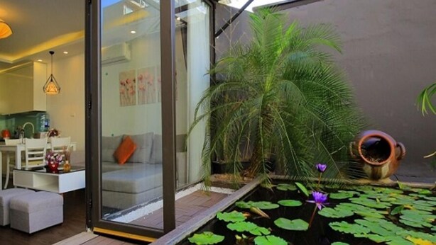 A modern interior with a glass door leading to a dining area, a small pond with water lilies, and a potted plant. - Sumitomo 11 APT - Alley 39 Linh lang (Hanoi)