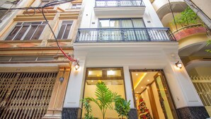 A multi-story building with balconies, a gated entrance, and potted plants. - Sumitomo 11 APT - Alley 39 Linh lang (Hanoi)