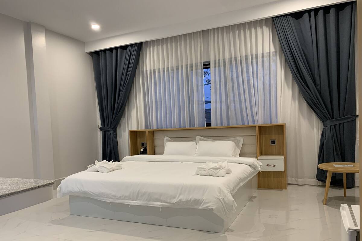 Un dormitorio moderno con una cama grande, mesitas de noche y una pequeña mesa redonda.