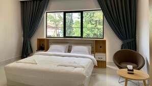 Een moderne hotelkamer met een groot bed, een nachtkastje, een stoel en een raam met gordijnen.