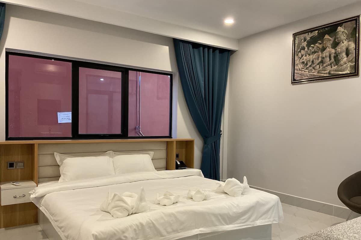 Una habitación de hotel moderna con una cama grande, una mesita de noche, un escritorio y una silla.