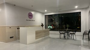 Een hotel receptie met een receptiebalie, een zithoek met stoelen en een groot raam met uitzicht op de straat.