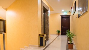 A hallway with a marble staircase, a door labeled "203", and two potted plants. - Sara Furnished Apartments (Al Khobar)