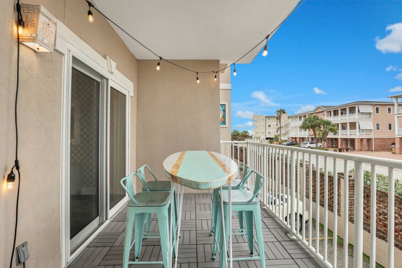 A balcony with a table and chairs, string lights, and a view of neighboring buildings.