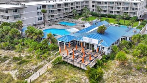 Een hotel met meerdere zwembaden, buitenzitplaatsen en een overdekt terras.