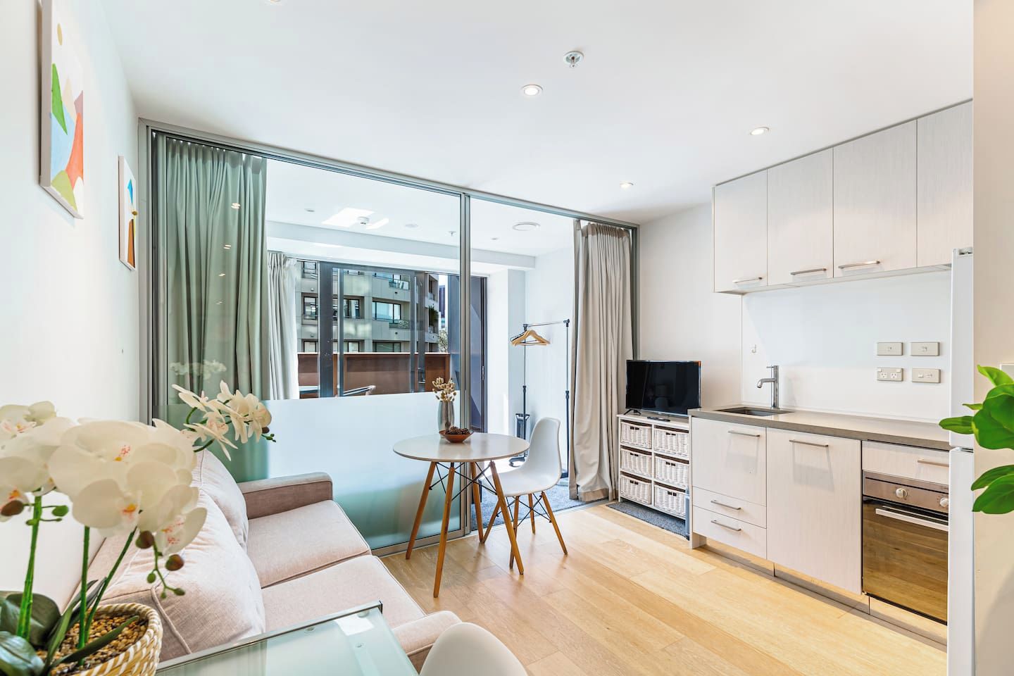A modern apartment with a dining area, kitchen, and large windows.