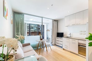 Un appartement moderne comprenant un salon, un coin repas, une cuisine et de grandes fenêtres.