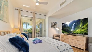 Une chambre spacieuse avec un grand lit, une télévision, une commode et une porte-fenêtre coulissante donnant sur un balcon.