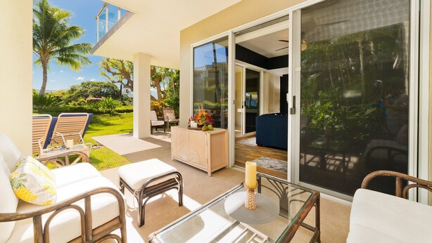 Une vaste terrasse extérieure avec une porte vitrée donnant sur un espace abrité, aménagé avec des chaises et une table.