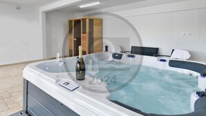 A modern spa room with a hot tub, two wine glasses, and a bottle of champagne.