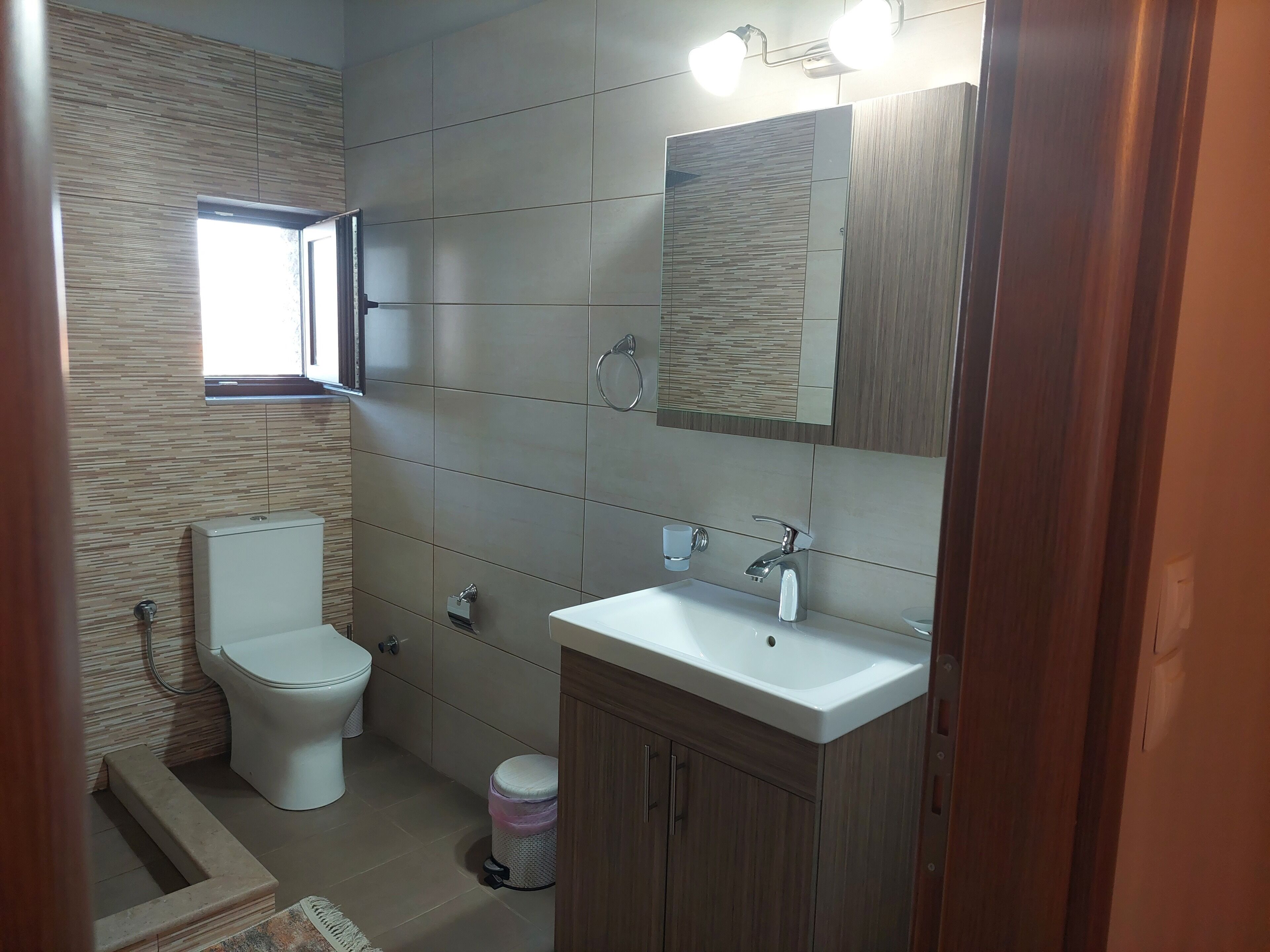Un baño moderno con inodoro, lavamanos y espejo.