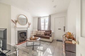 Ein Wohnzimmer mit Kamin, Sofa, Couchtisch und Fernseher.