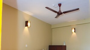 A hotel room with two wooden beds, a ceiling fan, and wall-mounted lights. - Lakers Bed and Breakfast (Pokhara)