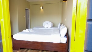 A hotel room with a wooden bed, white linens, and a small bedside table. - Lakers Bed and Breakfast (Pokhara)