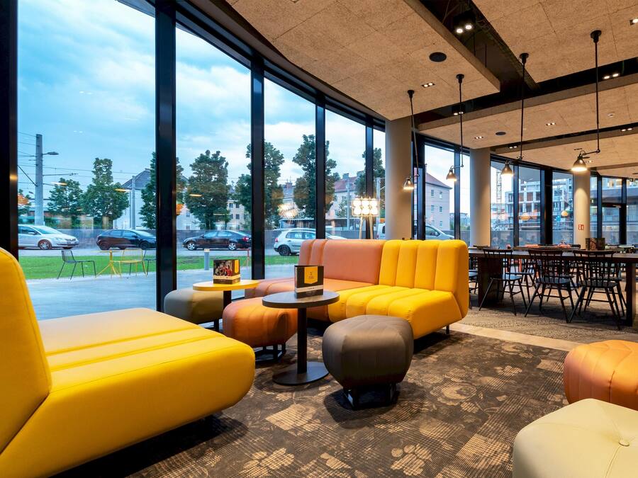 Een moderne lounge met grote ramen, comfortabele zitmogelijkheden en een eethoek.