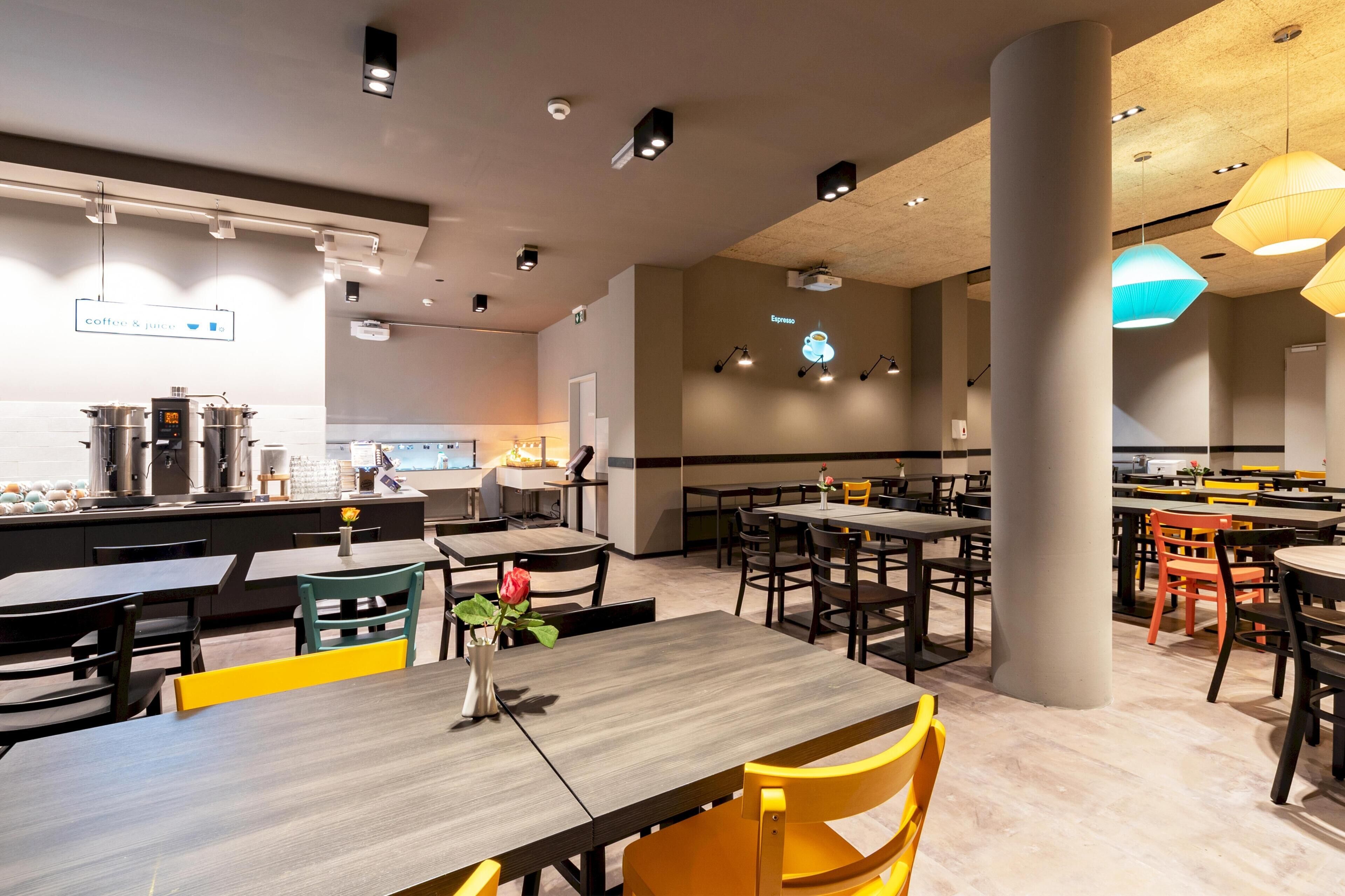 Un café moderno con varias mesas y sillas, una máquina de café y un letrero con el menú.