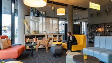 A modern hotel lobby with seating areas, a dog, and a 'Harry's Hotel' sign.
