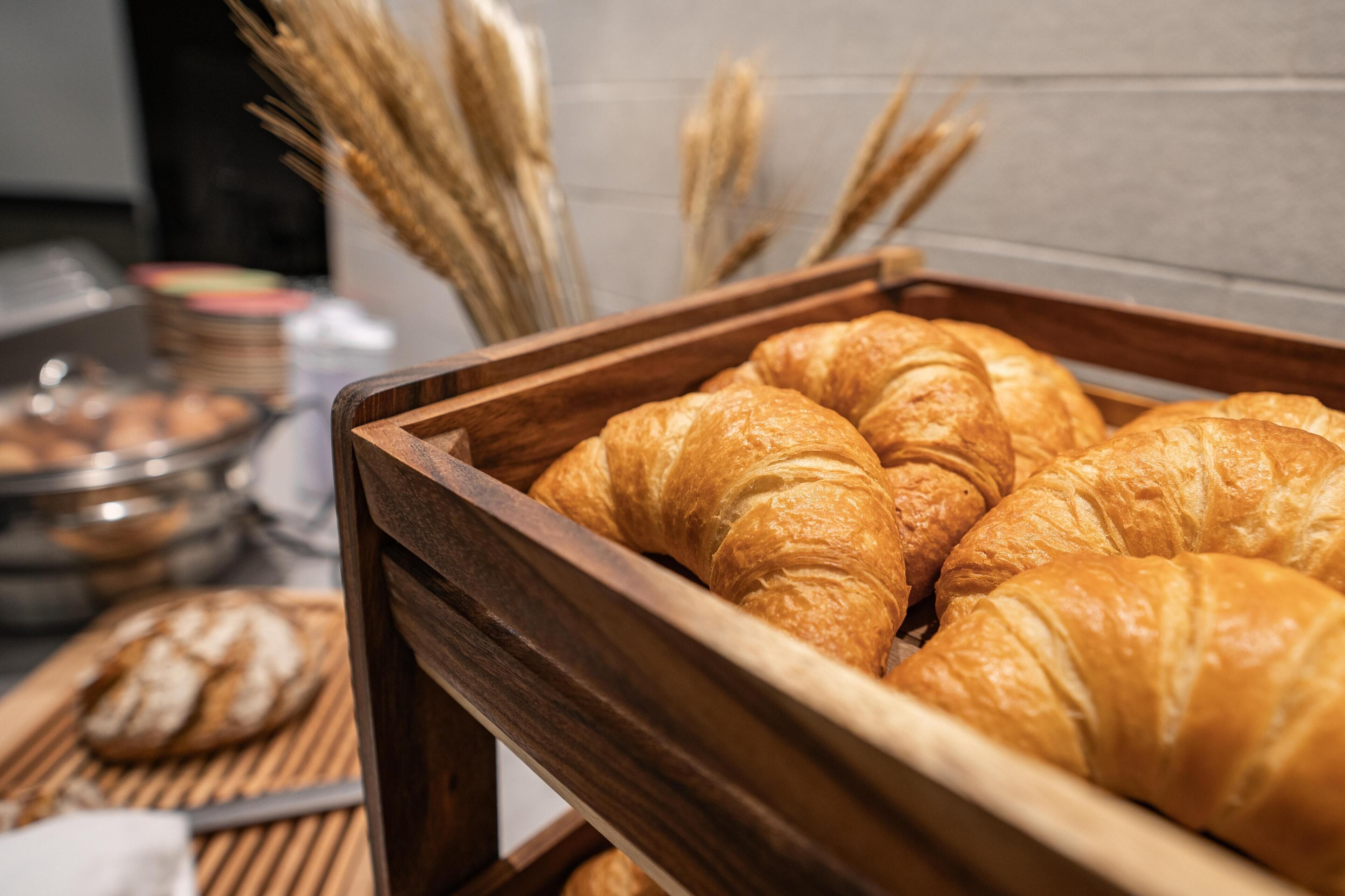 Una bandeja de madera con varios croissants dorados.