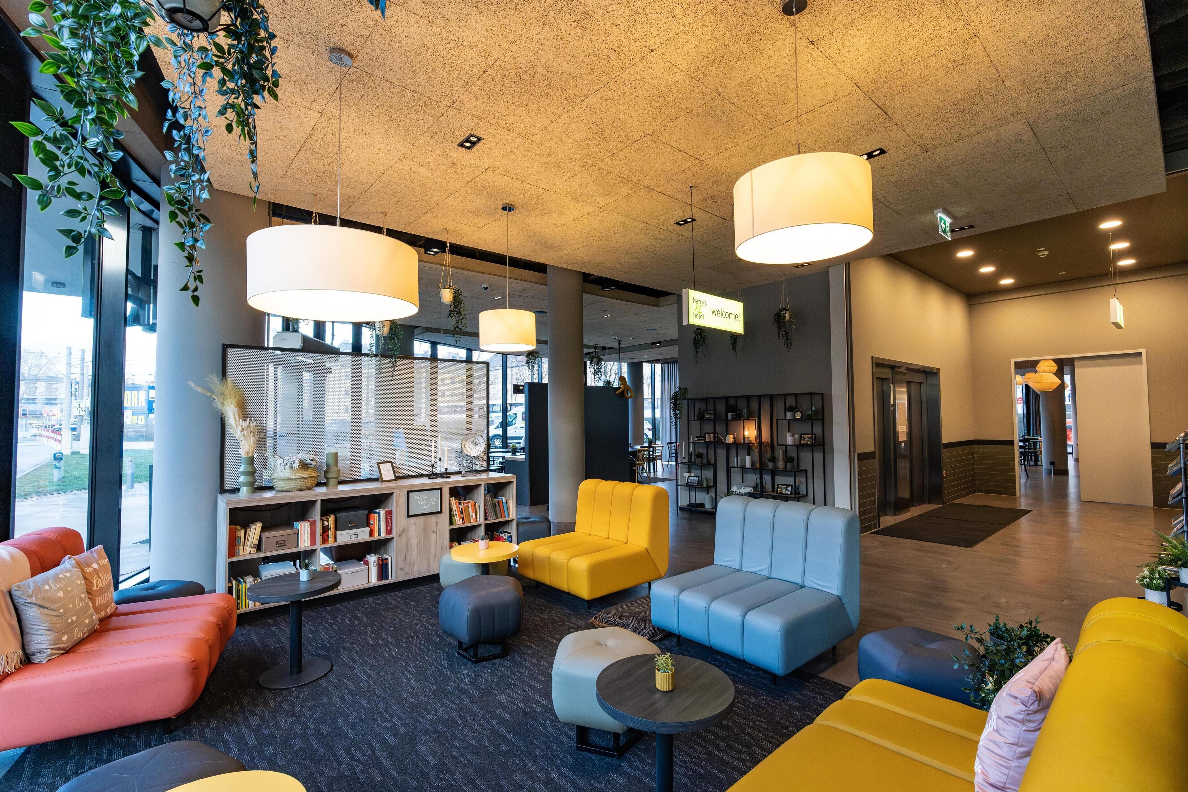 A modern lobby with seating areas, a reception desk, and a large window providing a view of the city.