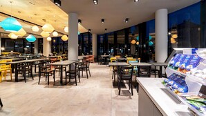 A modern restaurant with multiple dining areas, large windows, and a variety of seating options. - harry's home Salzburg (Salzburg)