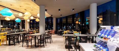 Een modern restaurant met verschillende eetgedeeltes, grote ramen en diverse zitmogelijkheden.