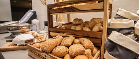 A wooden bread display with various types of bread and rolls.