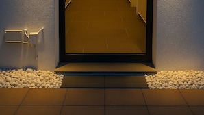 Een gang met een spiegelwand, inbouwverlichting en een deur aan het einde.