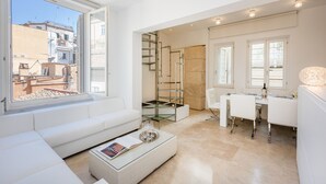 Uma sala de estar moderna com um sofá branco, uma mesa de centro de vidro e um espaço de jantar com uma mesa e cadeiras brancas.