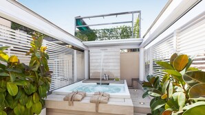 Uma área de spa moderna ao ar livre, com hidromassagem, degraus de madeira e vegetação exuberante.