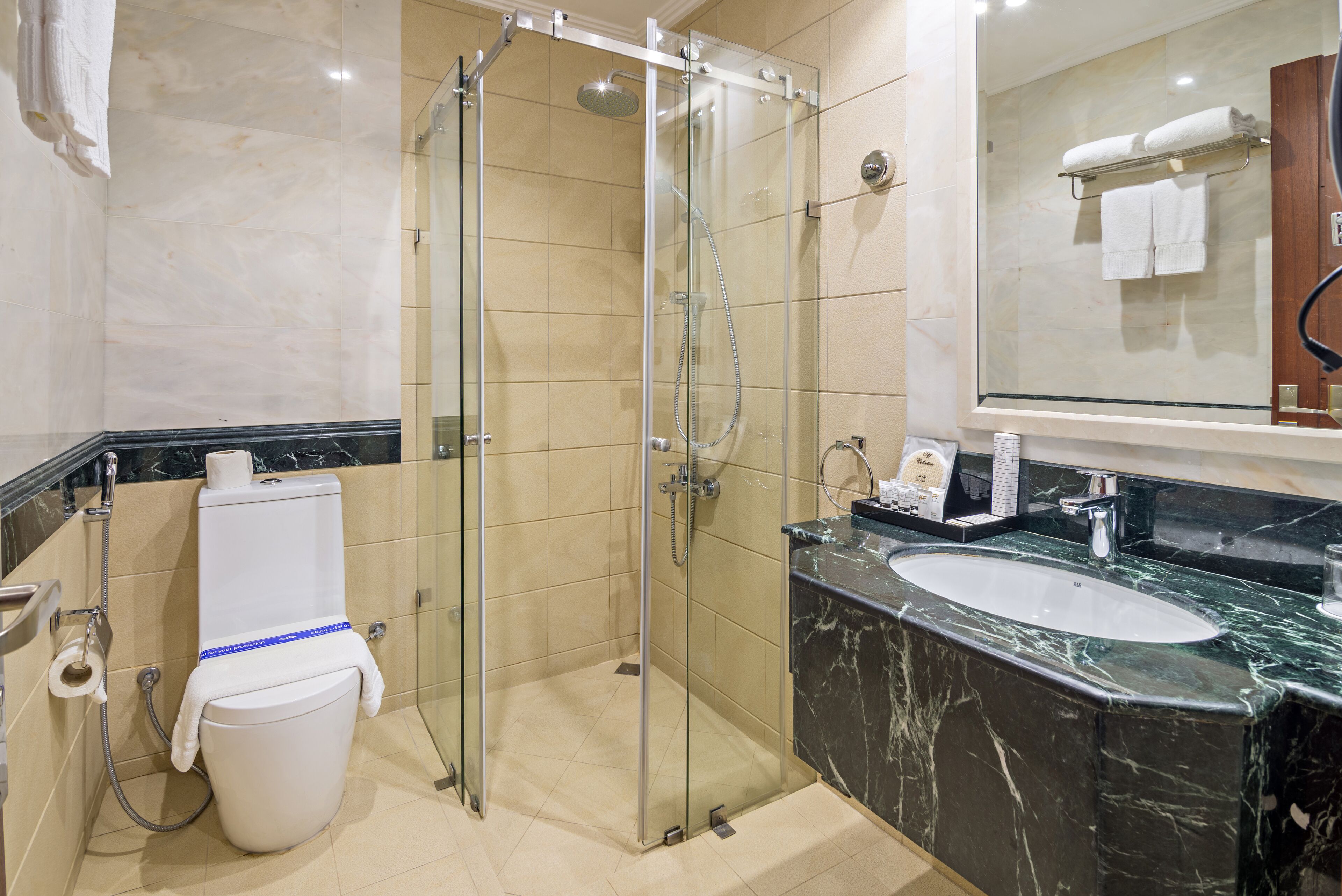A modern bathroom with a glass-enclosed shower, a marble sink, and a large mirror.