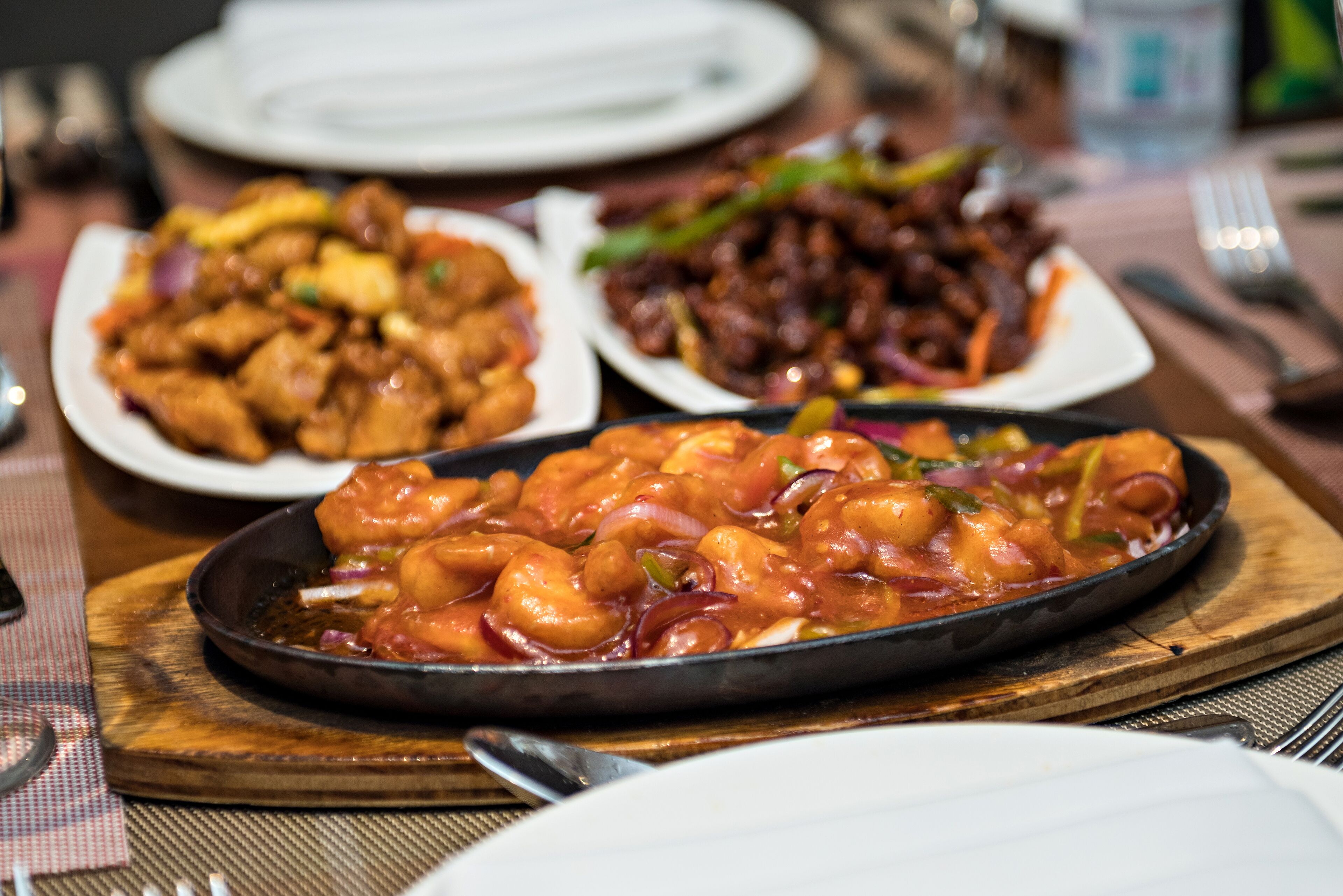 A table with various dishes including a shrimp dish, a chicken dish, and a bean dish.