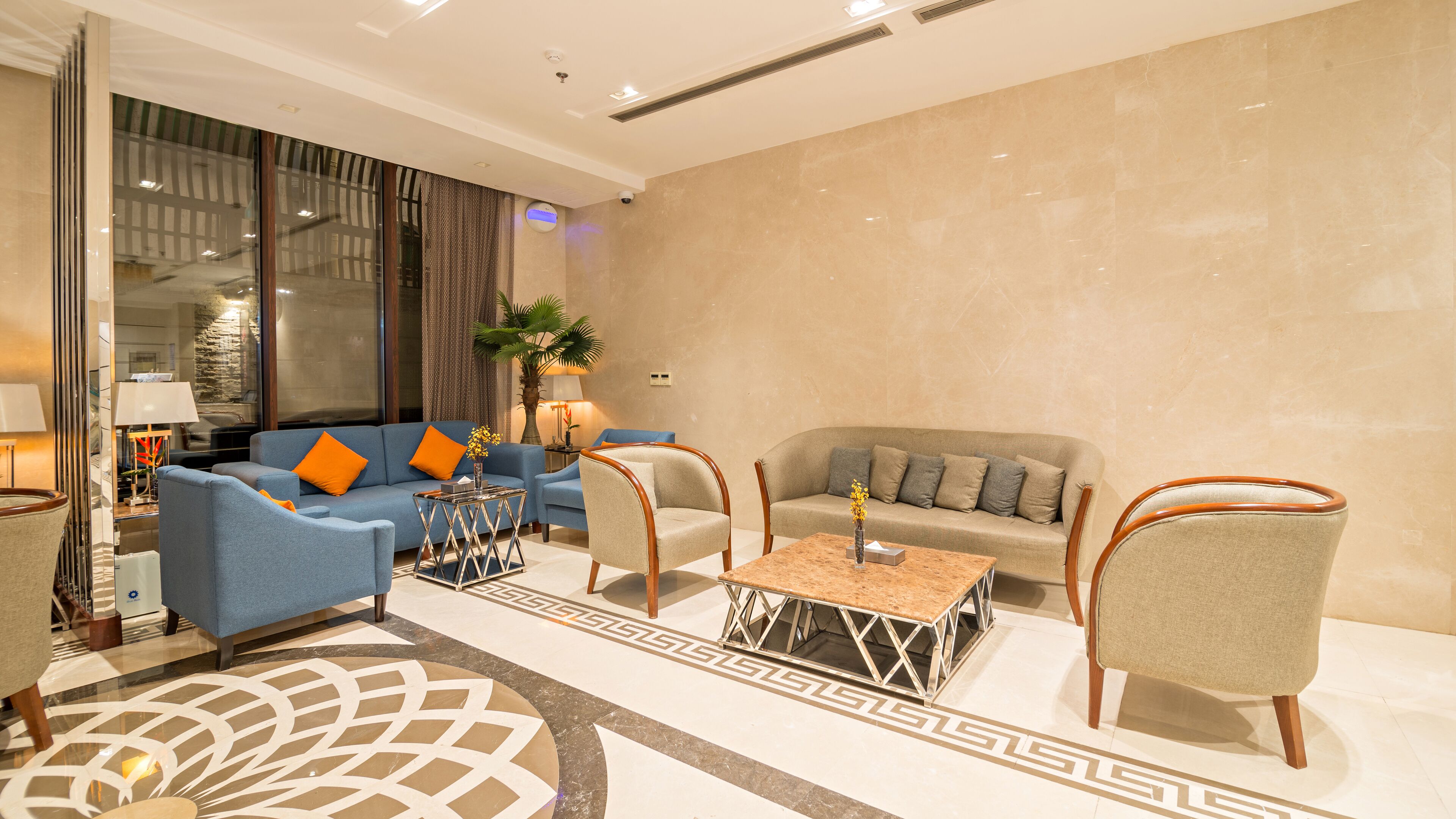 A modern living room with a blue sofa, a beige sofa, and two armchairs. There is a coffee table in the center.
