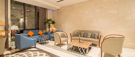 A modern living room with a blue sofa, a beige sofa, and two armchairs. There is a coffee table in the center.