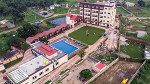 An aerial view of a hotel with multiple buildings, a swimming pool, and a green lawn. - JHARNA RESORT (Purulia)