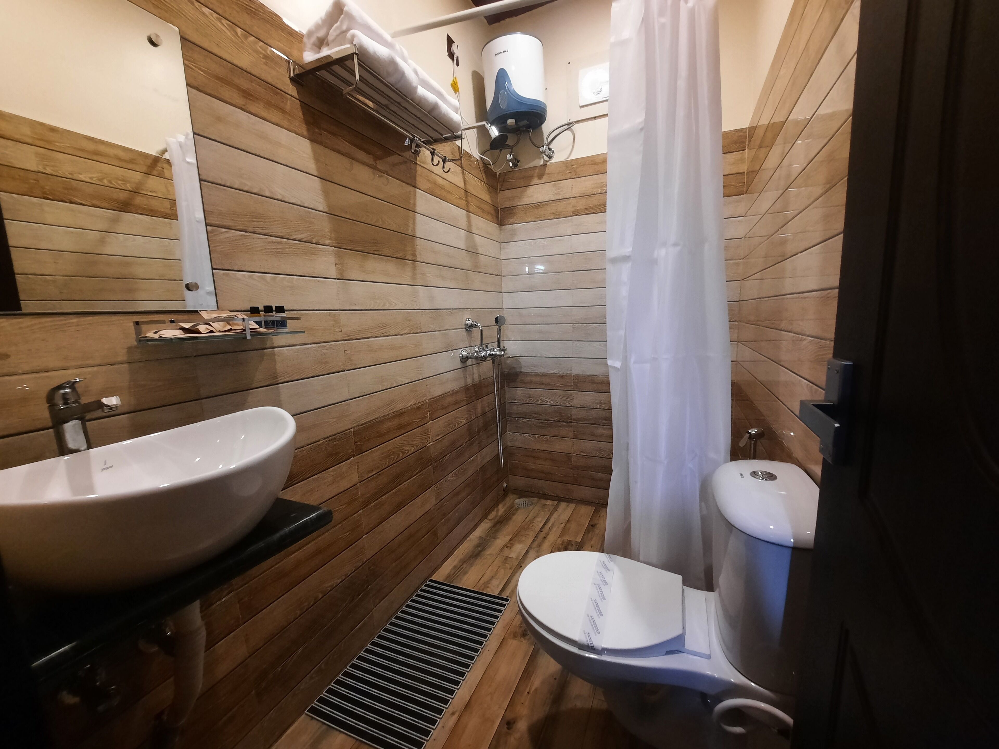 Ein Badezimmer mit Holzwand, Waschbecken, Toilette und Duschbereich.
