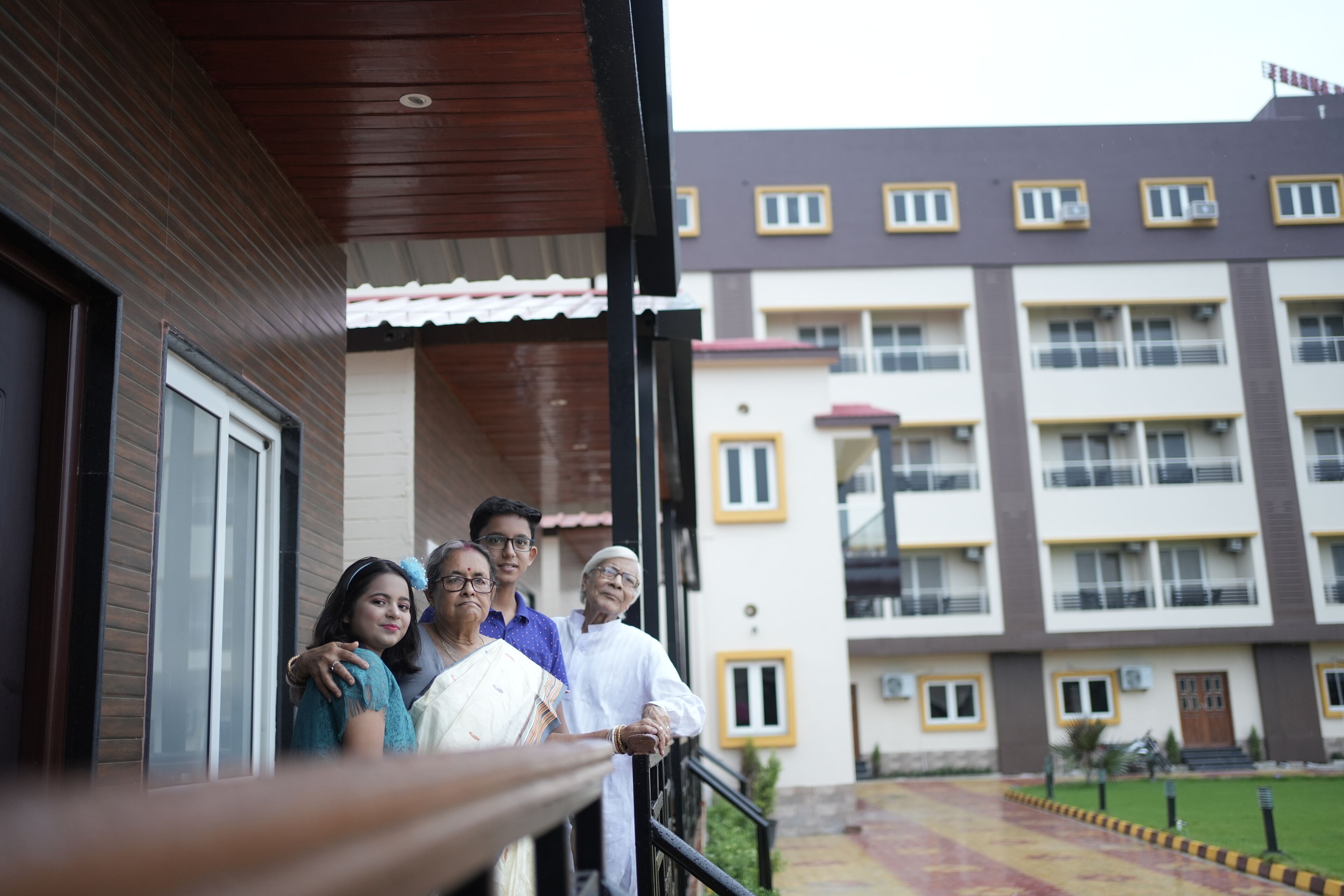 A group of people standing on a balcony with a view of a multi-story building with balconies and windows.