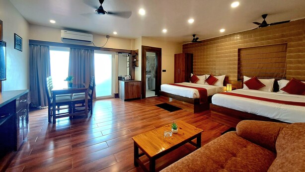 A hotel room with two beds, a sofa, a wooden coffee table, and a dining area with a table and chairs. - JHARNA RESORT (Purulia)