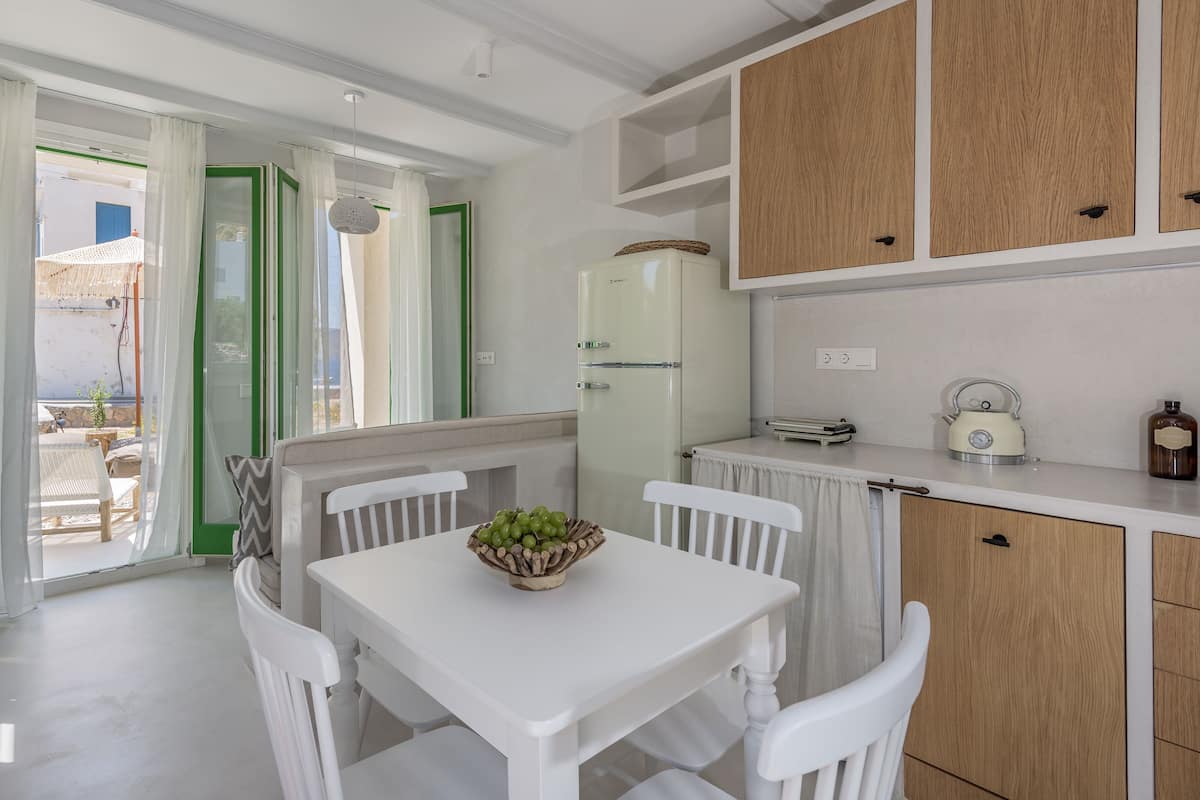 A modern kitchen with white cabinetry, a dining table with chairs, and a view of the outside.