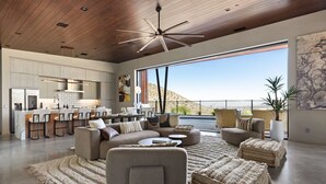 A spacious living area with a modern kitchen, a large window offering a view of the outdoors, and a ceiling fan.