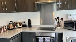 A modern kitchen with dark cabinets, a stainless steel range hood, a built-in oven, and a microwave. - Stunning One Bed Modern & Contemporary Chalet (Bridlington)